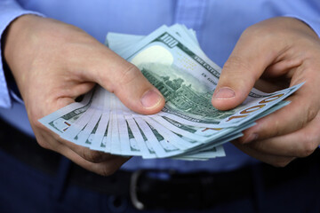 US dollars in male hand close up, man in business clothes counts the money. Concept of bribe,...