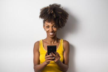 Young afro hairstyle casual black woman texting on smartphone and looking at camera.