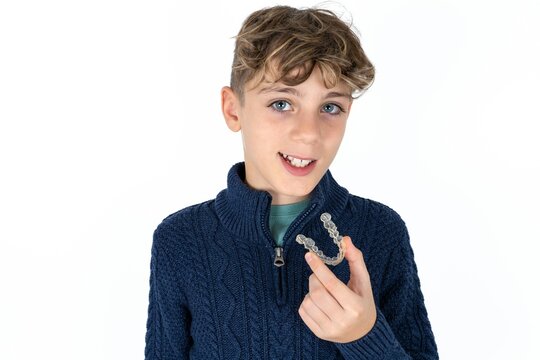 Caucasian teen boy holding an invisible aligner ready to use it. Dental healthcare and confidence concept.