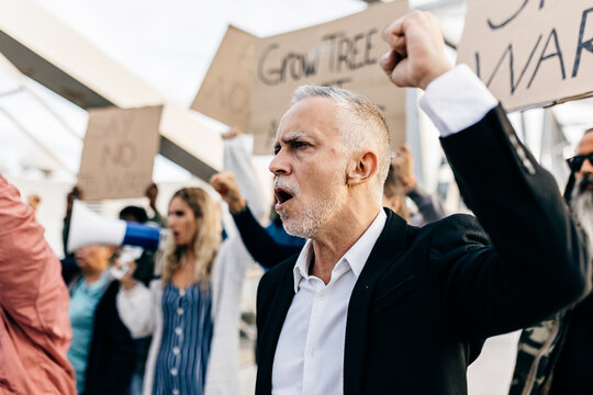 Group of diverse people protesting against war. Crowd of activist holding banners antiwar standing together for peace. - Powered by Adobe