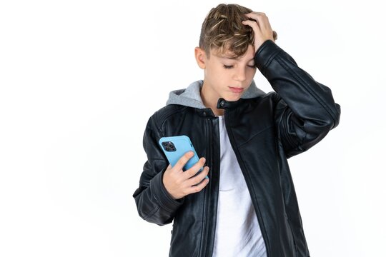Upset depressed Caucasian teen boy makes face palm as forgot about something important holds mobile phone expresses sorrow and regret blames