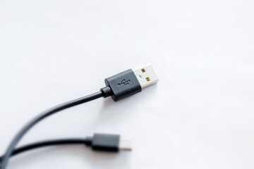 Close-up of black USB charging cable, compatible for many devices, isolated on white background.