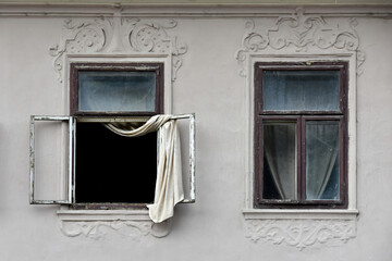 A loose curtain blows out of the window