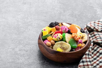 Sugar coated nuts and candied fruit in white plate on gray background