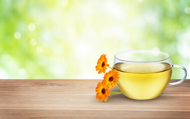 Glass cup of herbal tea with calendula marigold flowers. Natural hot drink