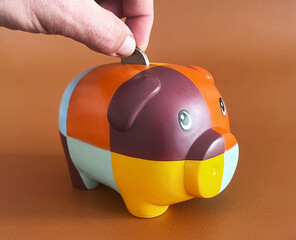 piggy bank with hand inserting a coin