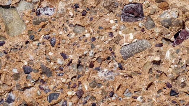 Rock with inclusions of different minerals moving sideways, close-up
