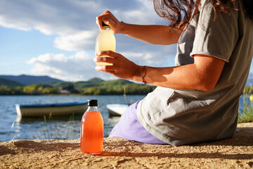 Unrecognizable woman opening a bottle of homemade fermented raw kombucha tea. Healthy natural...