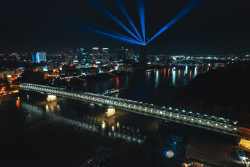 Aerial night shot of Bratislava city, bridges over the Danube river, and the vibrant nightlife lights in the city center.