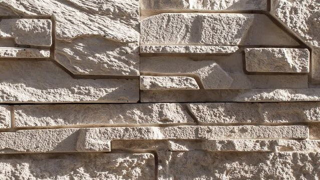 Wall, masonry of flat stones beige split uneven convex, moving sideways, close-up macro
