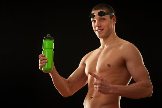 Muscular male swimer holding bottle