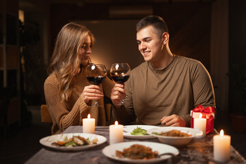 Romantic couple dating at night at home, cozy atmosphere, with glasses of red wine during romantic dinner on Valentines Day