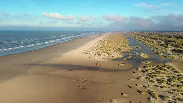 Aerial drone film of a golden beach with rolling waves in warm sunlight on island Terschelling