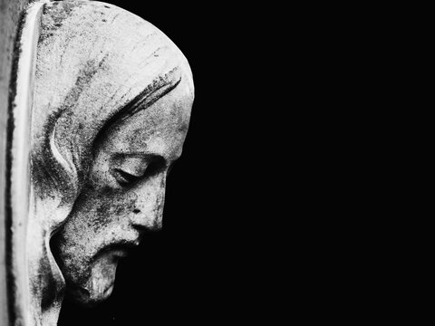 Face of Jesus Christ in profile on a black background. Black and white image of ancient statue. Copy space.