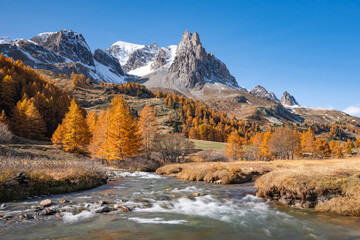 Autumn in Claree Valley in the French Alps with larch trees, Claree River, and Main de Crepin mountain peak. Cerces Massif, Hautes Alpes, France - 673782621