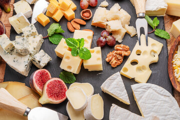 Variety of sliced cheeses with fruits, mint, nuts and cheese cutting knives. - Powered by Adobe