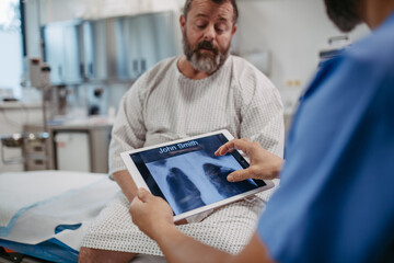 Doctor showing overweight patient chest x-ray, discussing test result in emergency room....