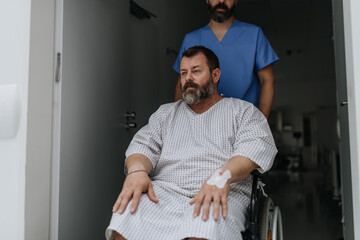 Male nurse pushing a patient in a wheelchair along a hospital corridor. Overweight patient feeling...