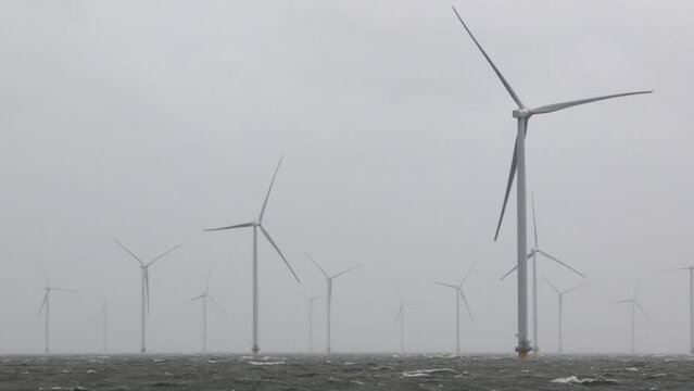 Large offshore windmills, turbines for alternative green, renewable energy, electricity, just of the Dutch coast in high winds, stormy weather, storm. High waves, dramatic. IJsselmeer, the Netherlands
