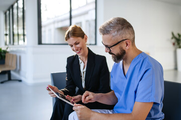 Pharmaceutical sales representative talking with doctor in medical building. Ambitious female sales...