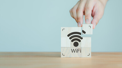 Hand put a wifi icon on wooden cube on wood table. Wifi icon on wooden cube block for service in the cafe. Business communication social network, Wireless network and connection technology concept. - obrazy, fototapety, plakaty