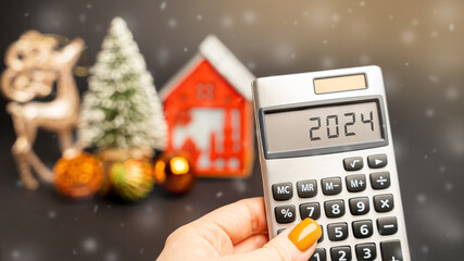 Calculator 2024, Christmas tree and miniature houses. Accumulating money and planning a budget....