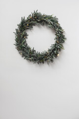 Christmas wreath at white wall with copyspace, winter holiday xmas background