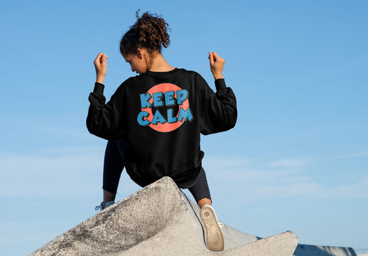 Mockup of woman wearing customizable sweatshirt on wall, arms raised