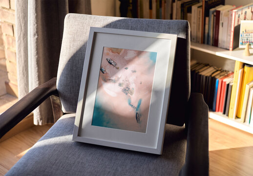 Mockup of vertical customizable wooden picture frame on chair