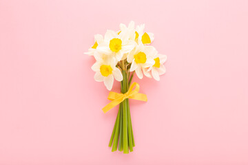 Beautiful fresh white narcissus flower bouquet with yellow ribbon on light pink table background....