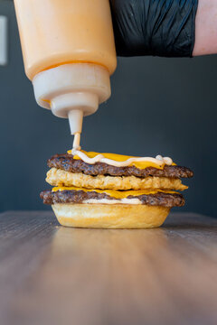 puting mayoneese on a hashbrown hamburger with cheese