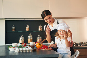 Eating pepper. Mother with her daughter are preparing food on the kitchen