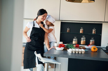 Taking a break. Mother with her daughter are preparing food on the kitchen