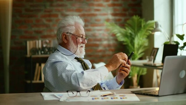 Elderly man company boss done job, satisfied leaning back and relaxing after hard working day finished project sending phone message and relaxing 