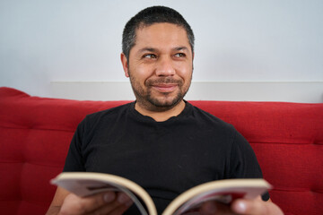 Joyful Man on Couch with Book Laughs
