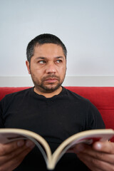 Reflective Man on Sofa with Book