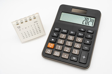 Calculator with the number 2024 on the display and Calendar DEC 2023. Concept of finance, taxes,...