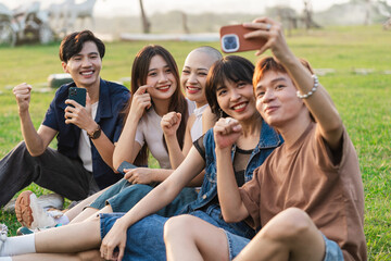 Image of a group of young Asian people laughing together and using their phones