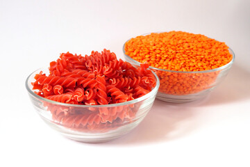 Red lentil fusilli pasta. Bowls with raw pasta and red lentils