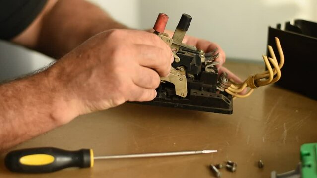 An electrician inspects an electrical appliance and tests the functionality of the buttons with his finger.