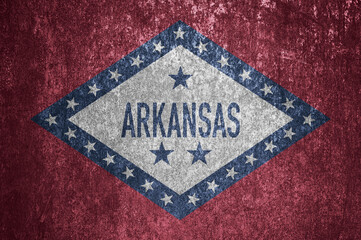 Close-up of the grunge Arkansas state flag. Dirty Arkansas state flag on a metal surface.