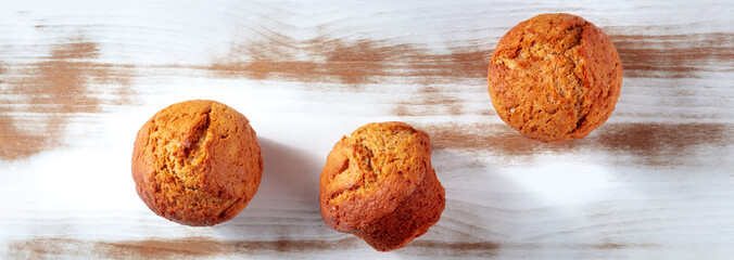 Orange muffins panorama on a rustic wooden kitchen table, easy baking, overhead flat lay shot