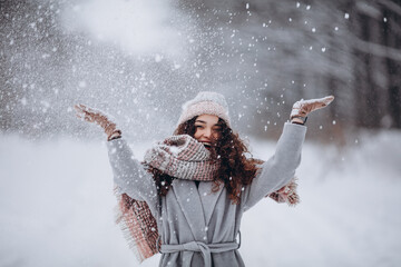 Happy active girl having fun and throwing snow in winter forest - obrazy, fototapety, plakaty
