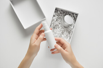 a woman unpacks a package with cosmetics and takes out cream from the box, top view