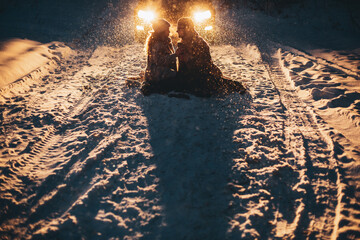 Young couple in love holding hands outdoor in winter at night with lights on background. Christmas...