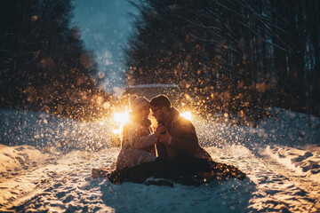 Young couple in love holding hands outdoor in winter at night with lights on background. Christmas...