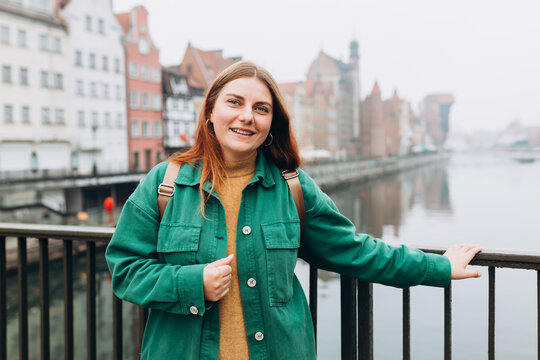 Attractive young female tourist is exploring new city. Gdansk old town and famous Zuraw crane, A happy beautiful woman is standing near Motlawa river
