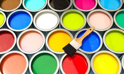 group of cans filled with coloured paint with brush.