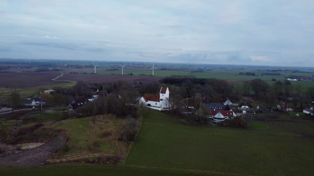 Aerial of a Bromme Parish church in Soro, Denmark with wind turbines in the background