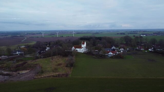 Aerial of a Bromme Parish church in Soro, Denmark with wind turbines in the background